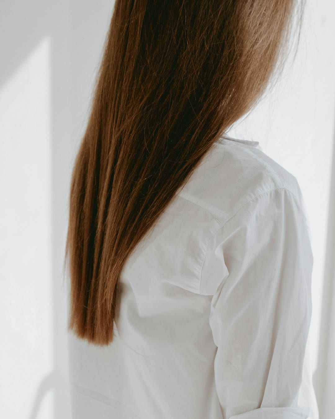 Glattes braunes Haar über einem weißen Hemd.